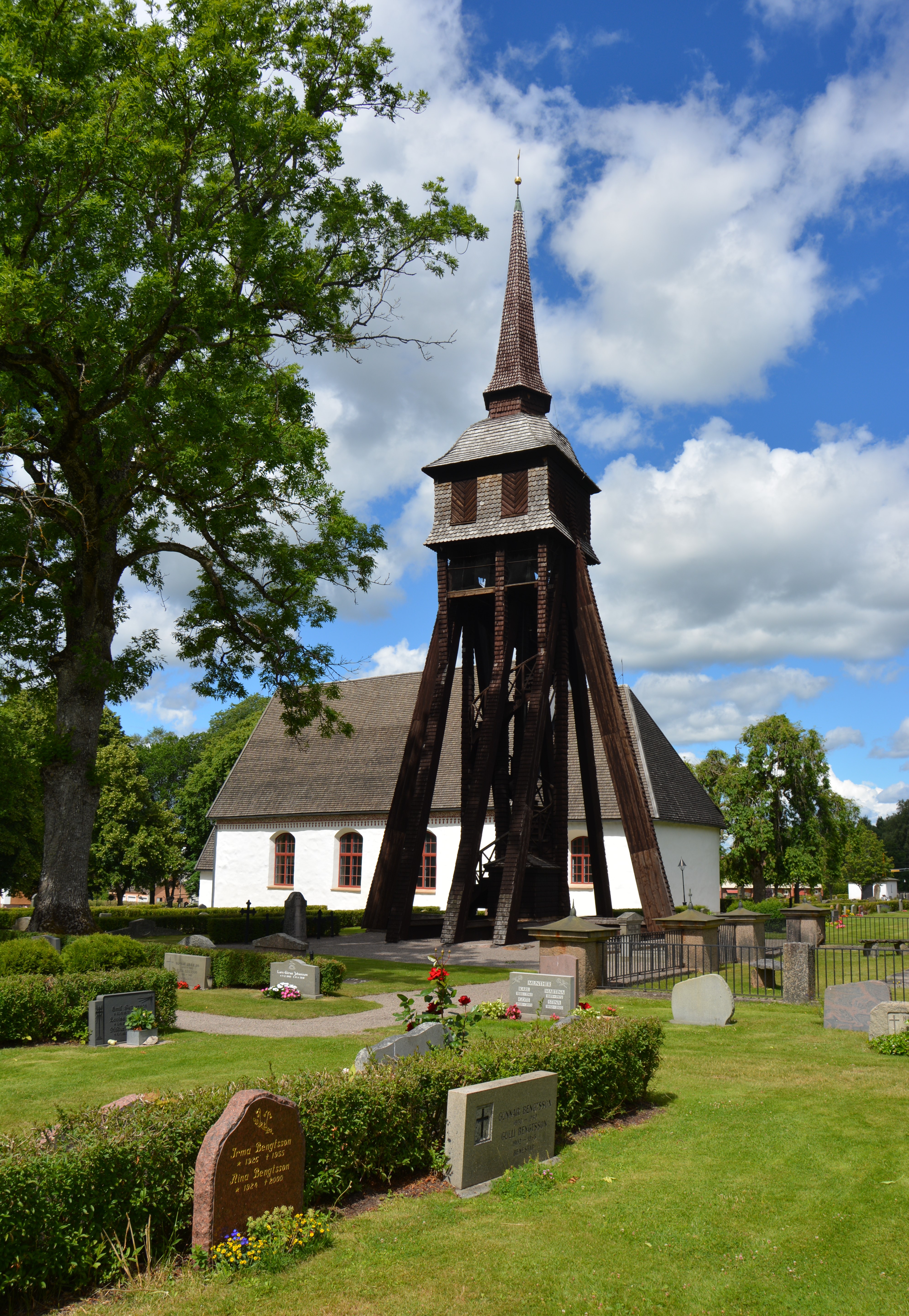 Alvesta kyrka, stenkyrka med torn mot sommarhimmel.