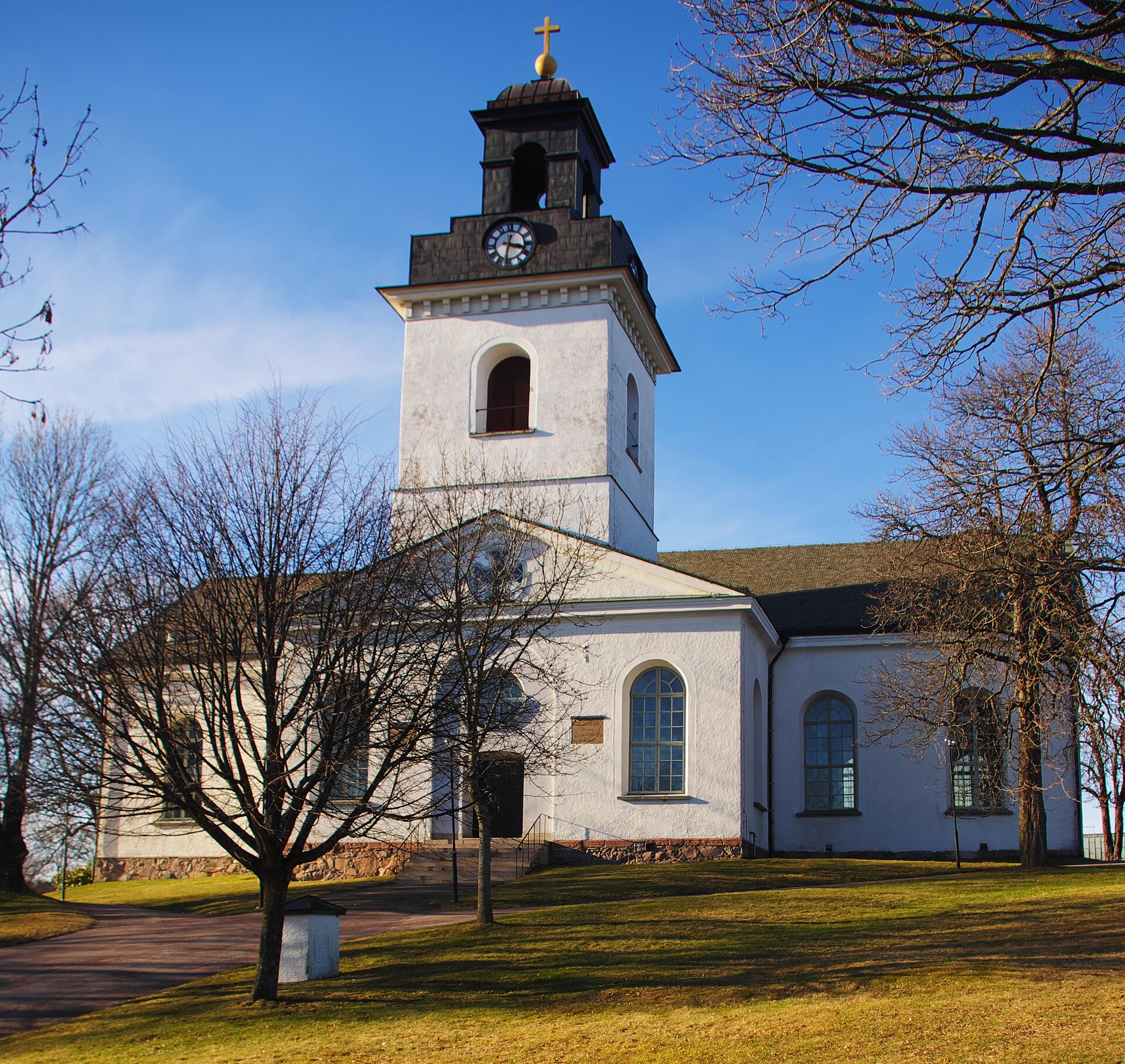 Åmåls kyrka, kyrka med torn mot sommarhimmel.