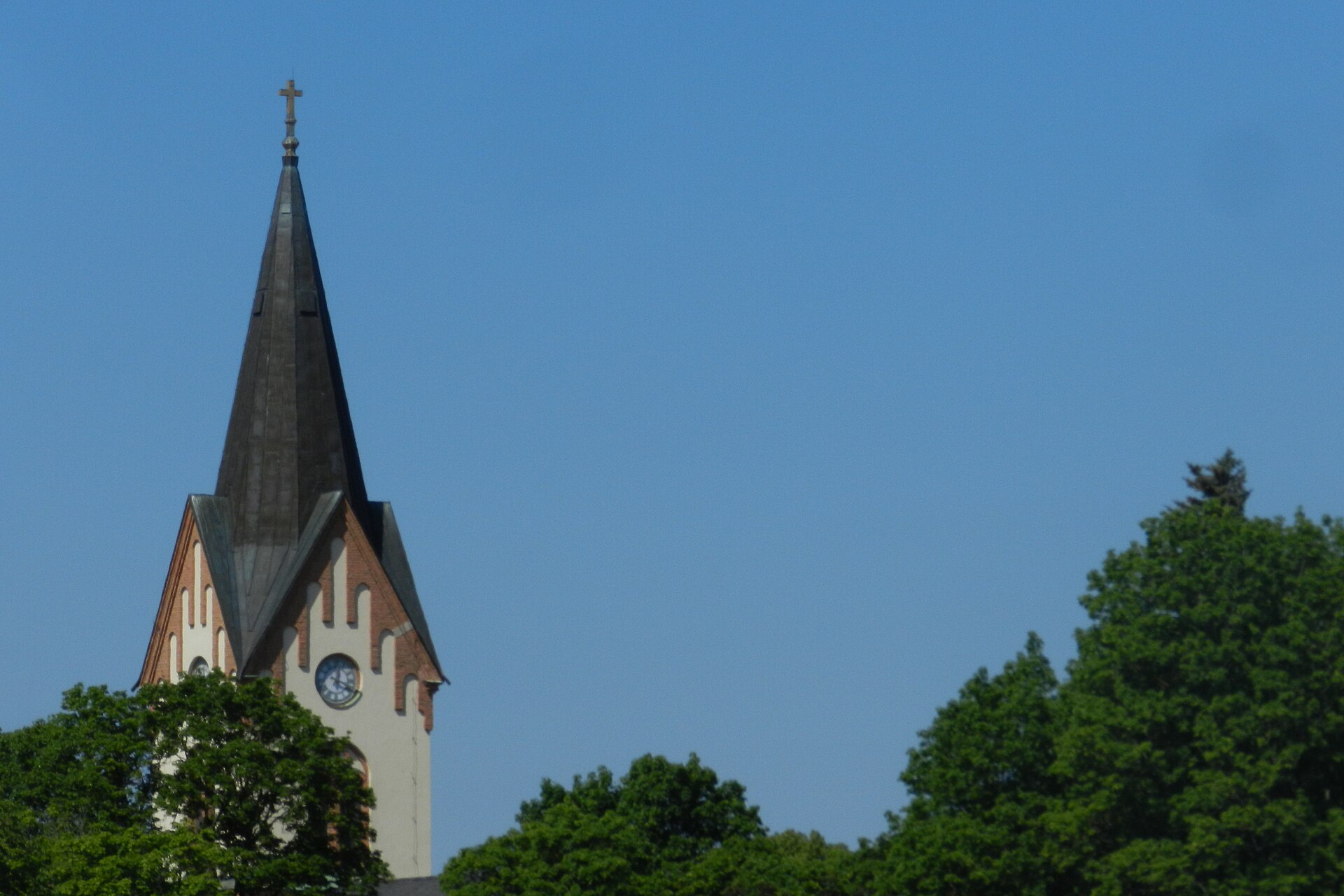 Avesta kyrka, stenkyrka med torn mot sommarhimmel.
