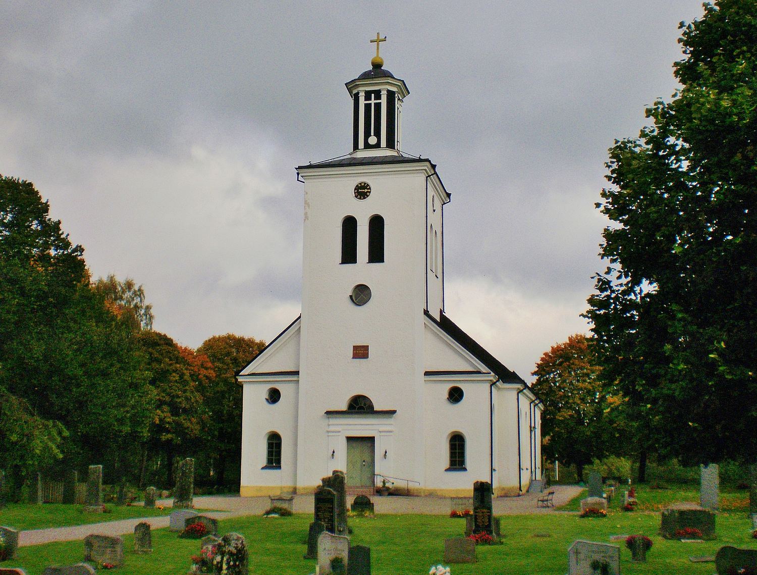 Björkö kyrka i Småland, en vit träkyrka omgiven av grönska.