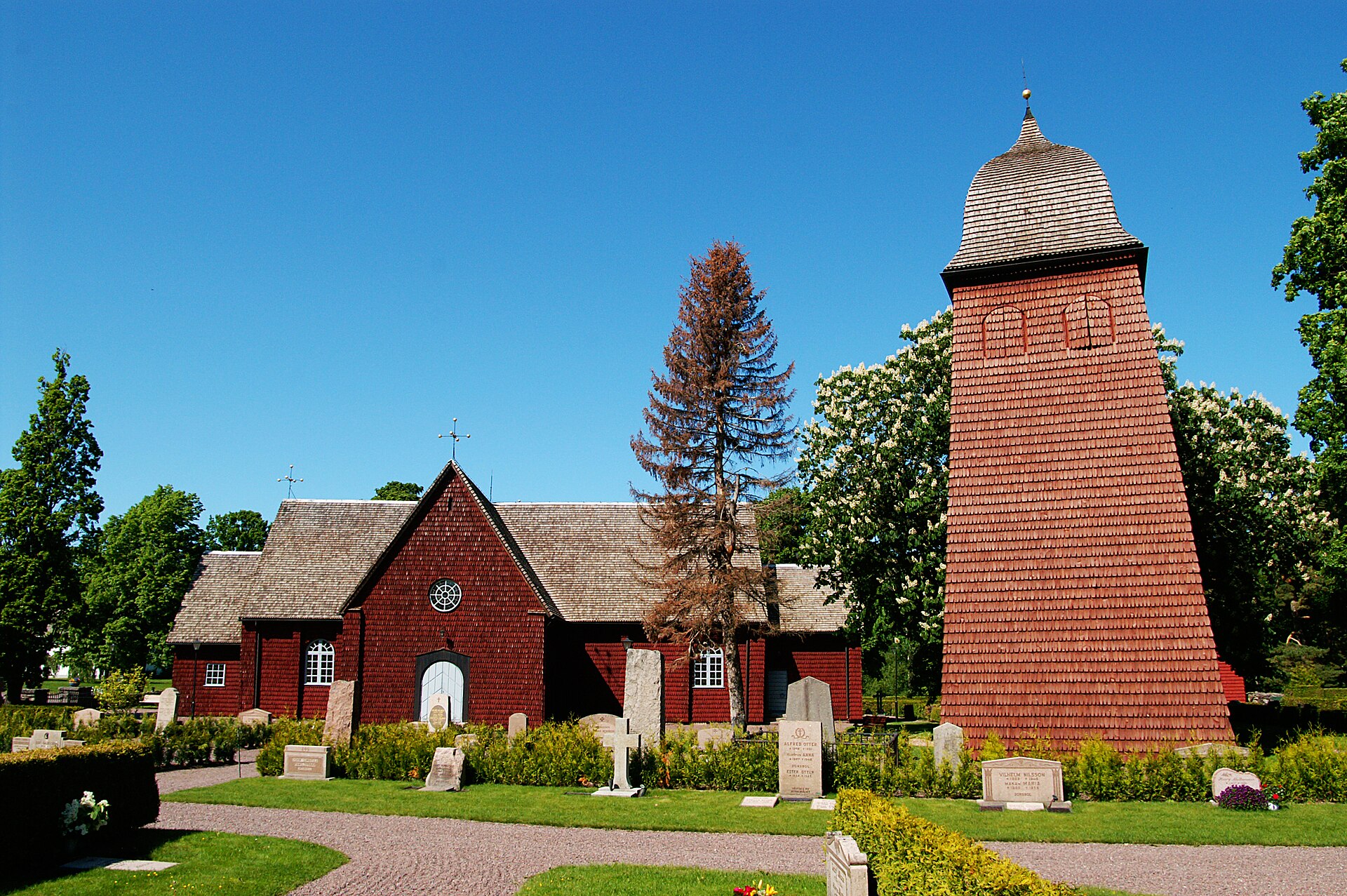 Hammarö kyrka, vit kyrka med svart tak och kyrkogård.
