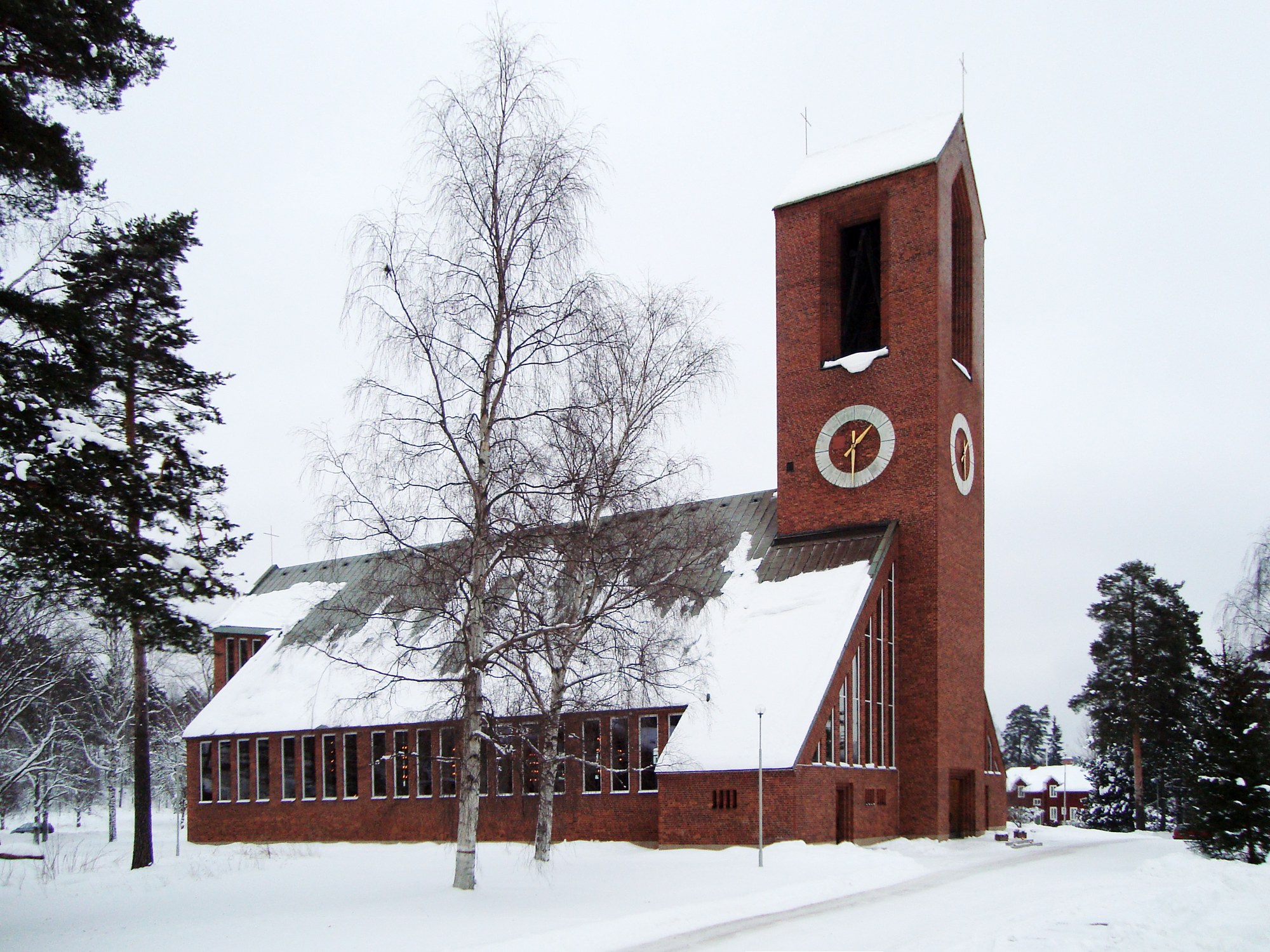 Hofors kyrka, stenkyrka med torn mot vinterhimmel.