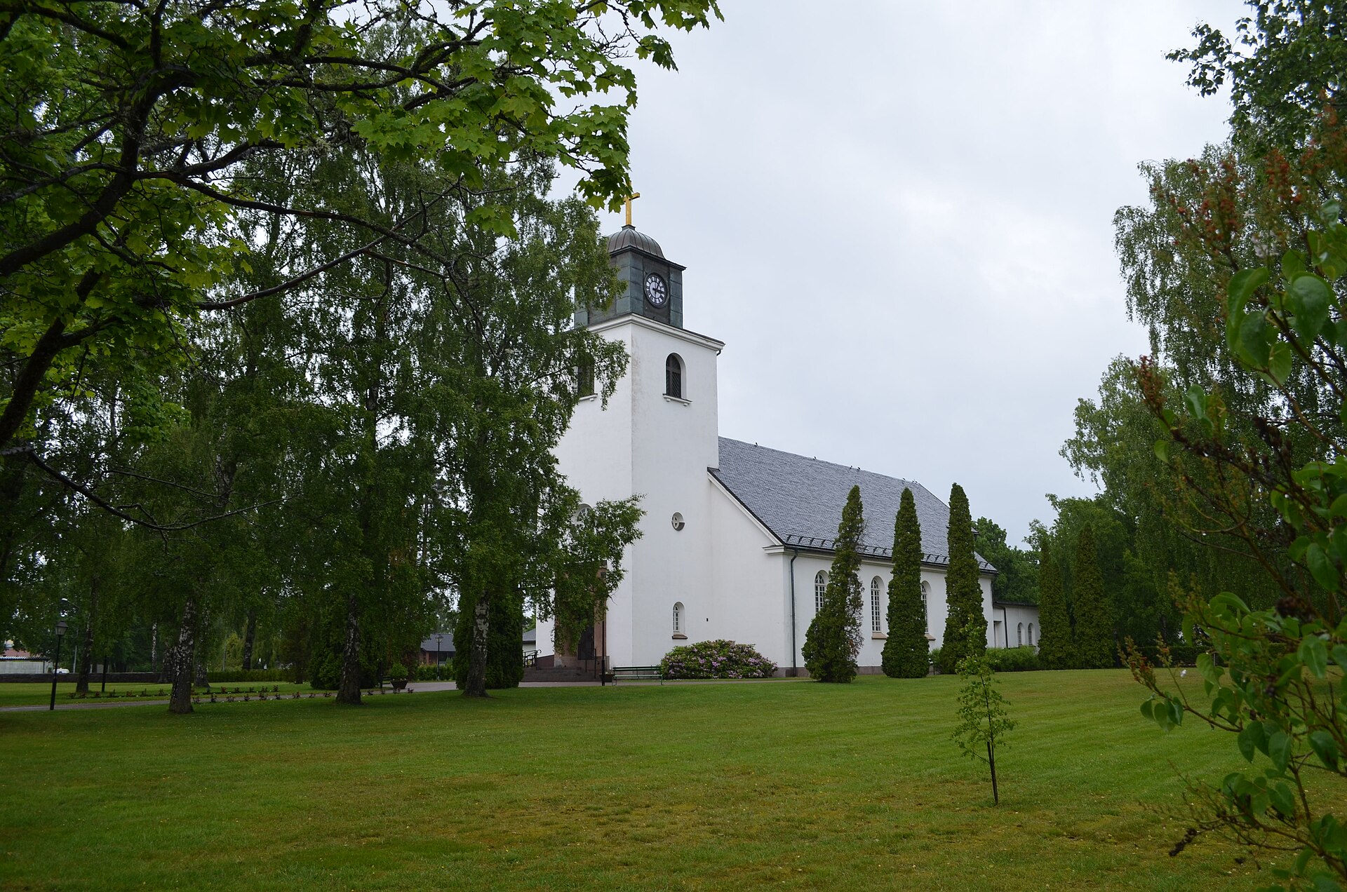 Hultsfreds kyrka, tegelkyrka med torn mot himlen.