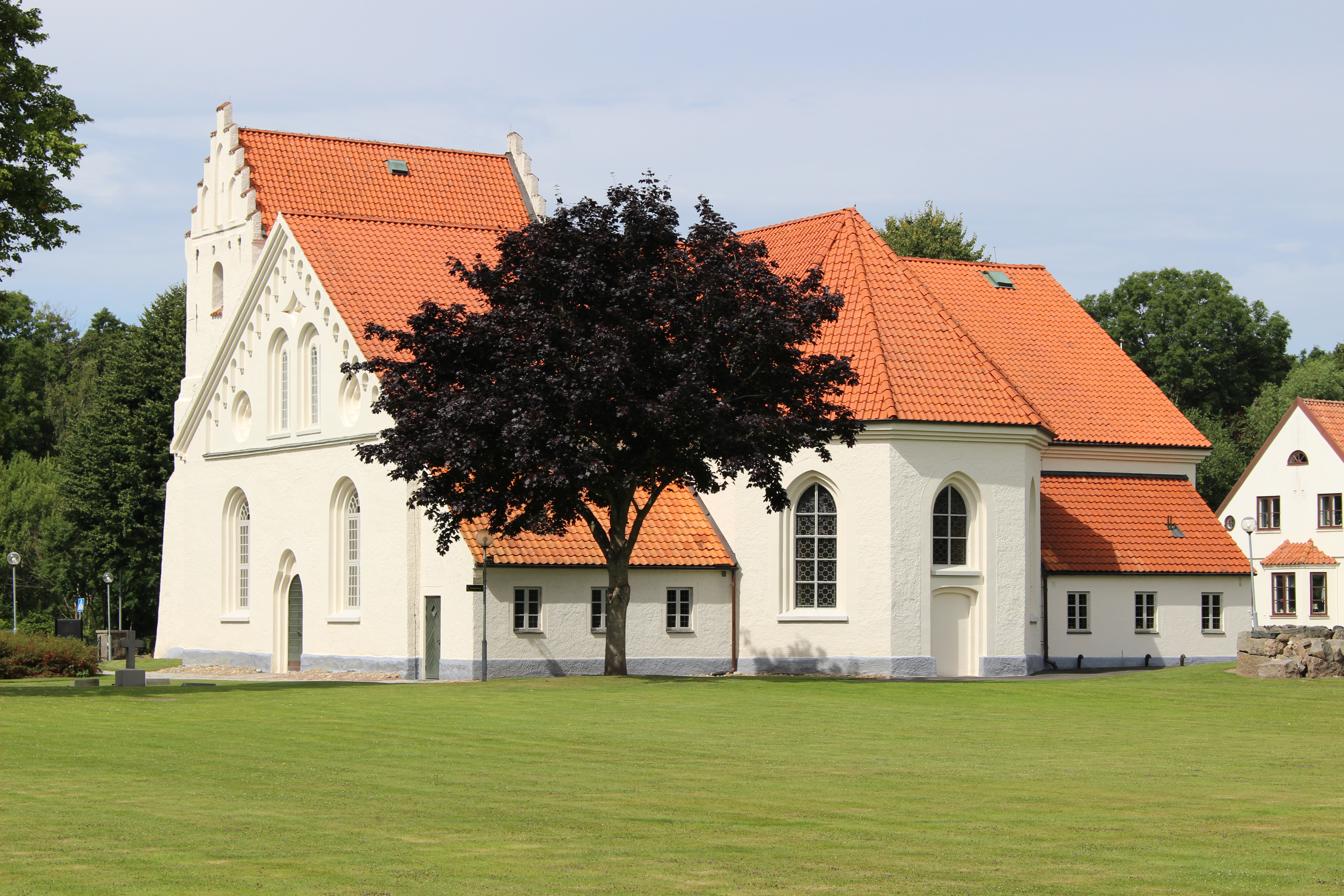 Ivetofta kyrka i Bromölla, vit kyrka med svart tak och kyrkogård.