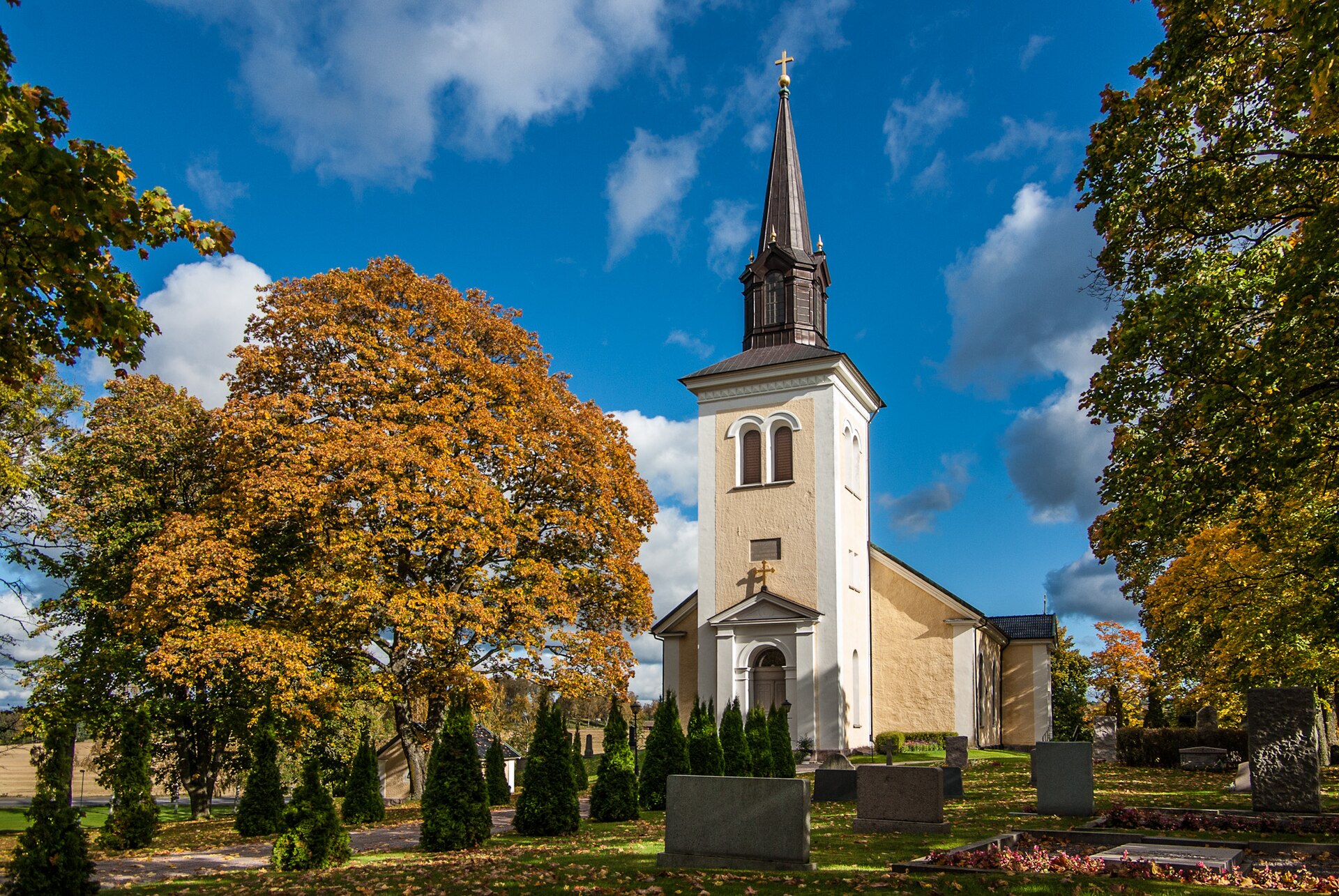 Kyrkefalla kyrka i Tibro, vit kyrka med svart tak och torn.