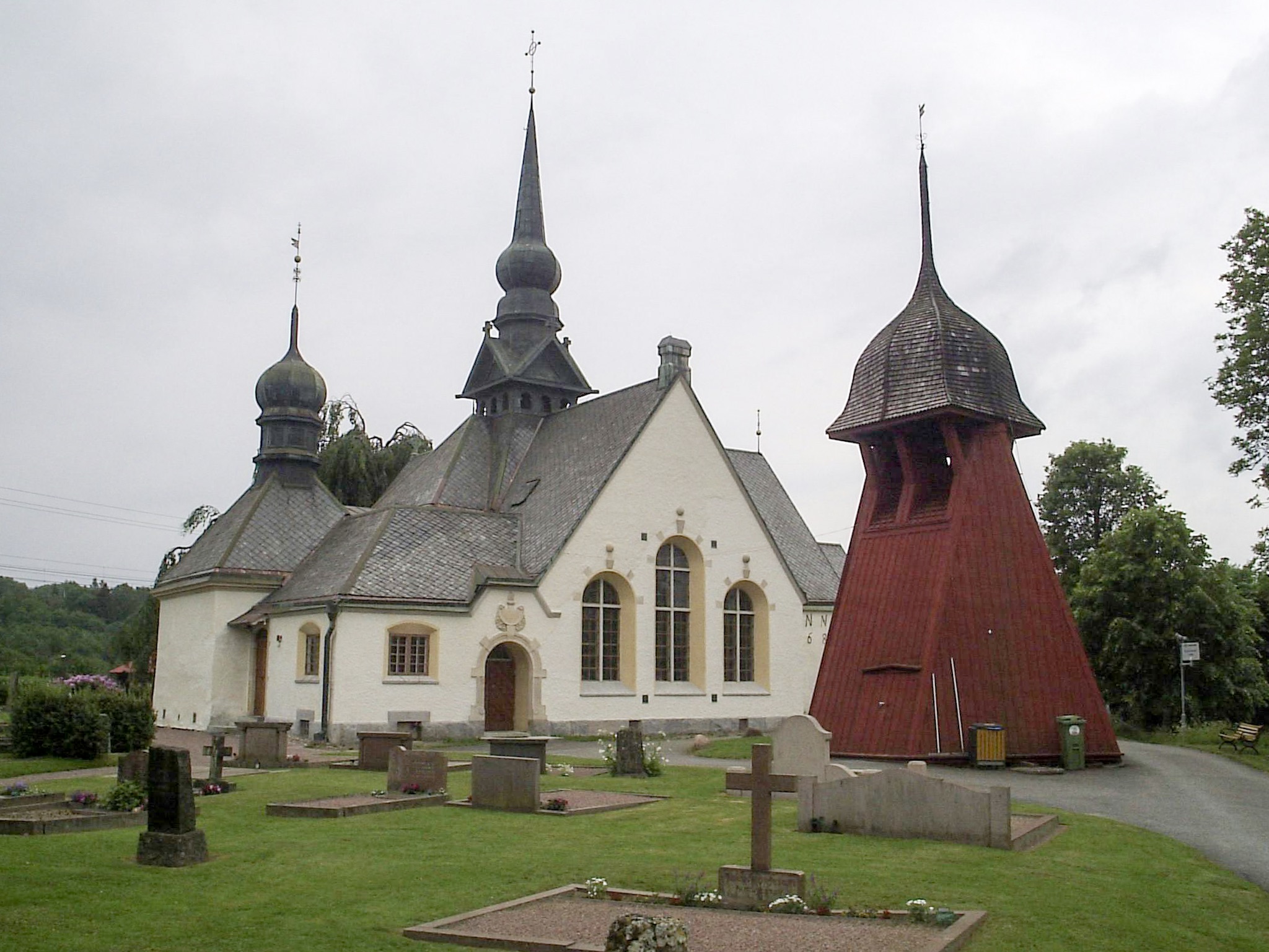 Lerums kyrka, stenkyrka med torn mot sommarhimmel.