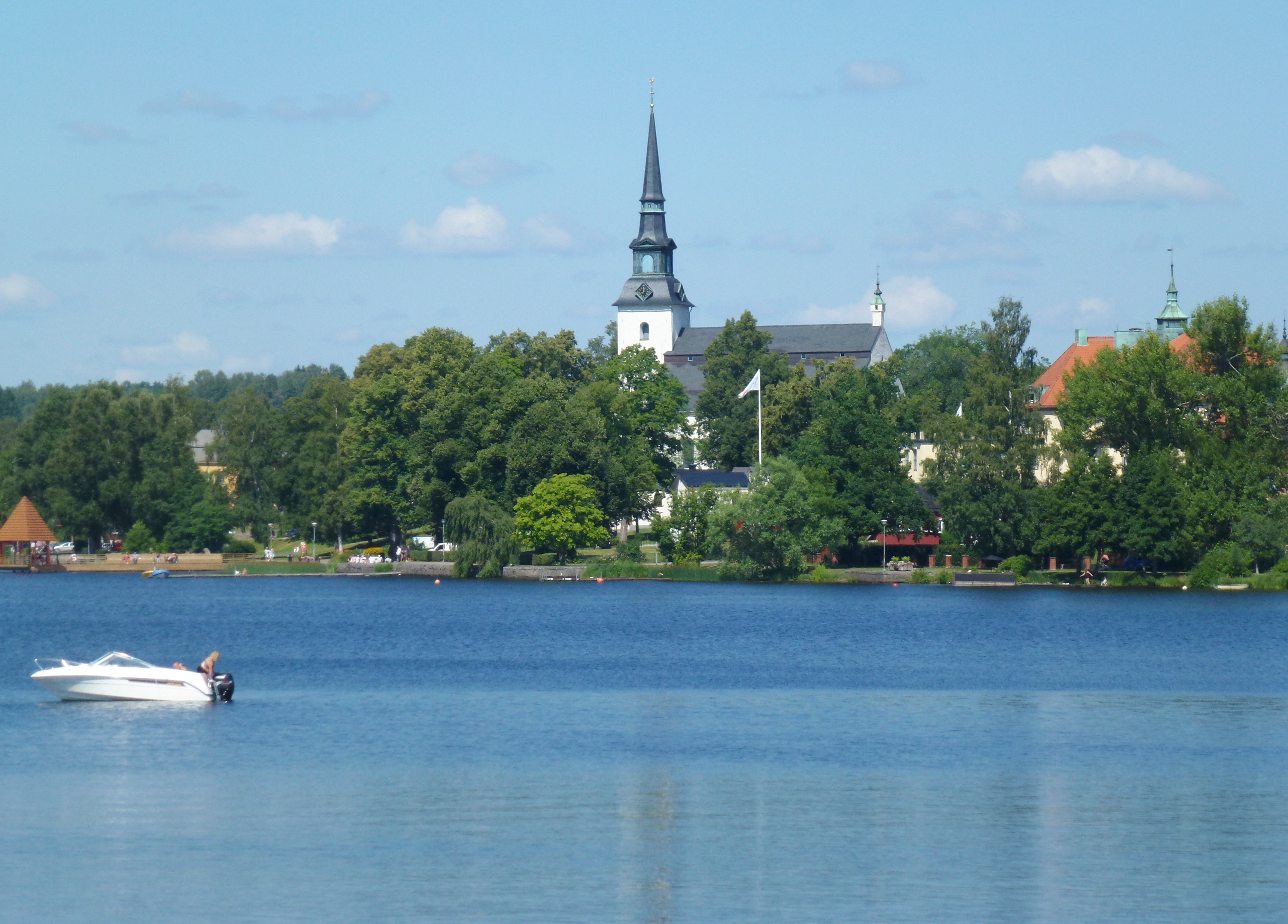 Lindesbergs kyrka, stenkyrka med torn mot sommarhimmel.