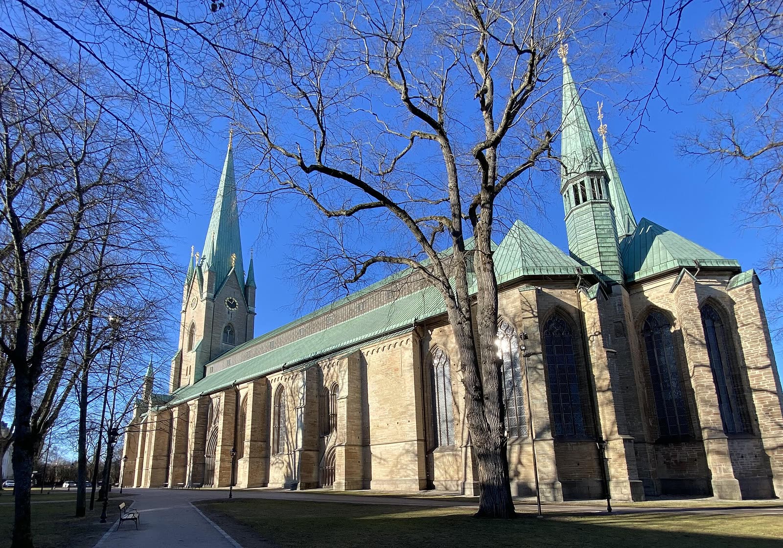 Linköpings domkyrka sett från domkyrkoparken, tegel och torn mot himlen.