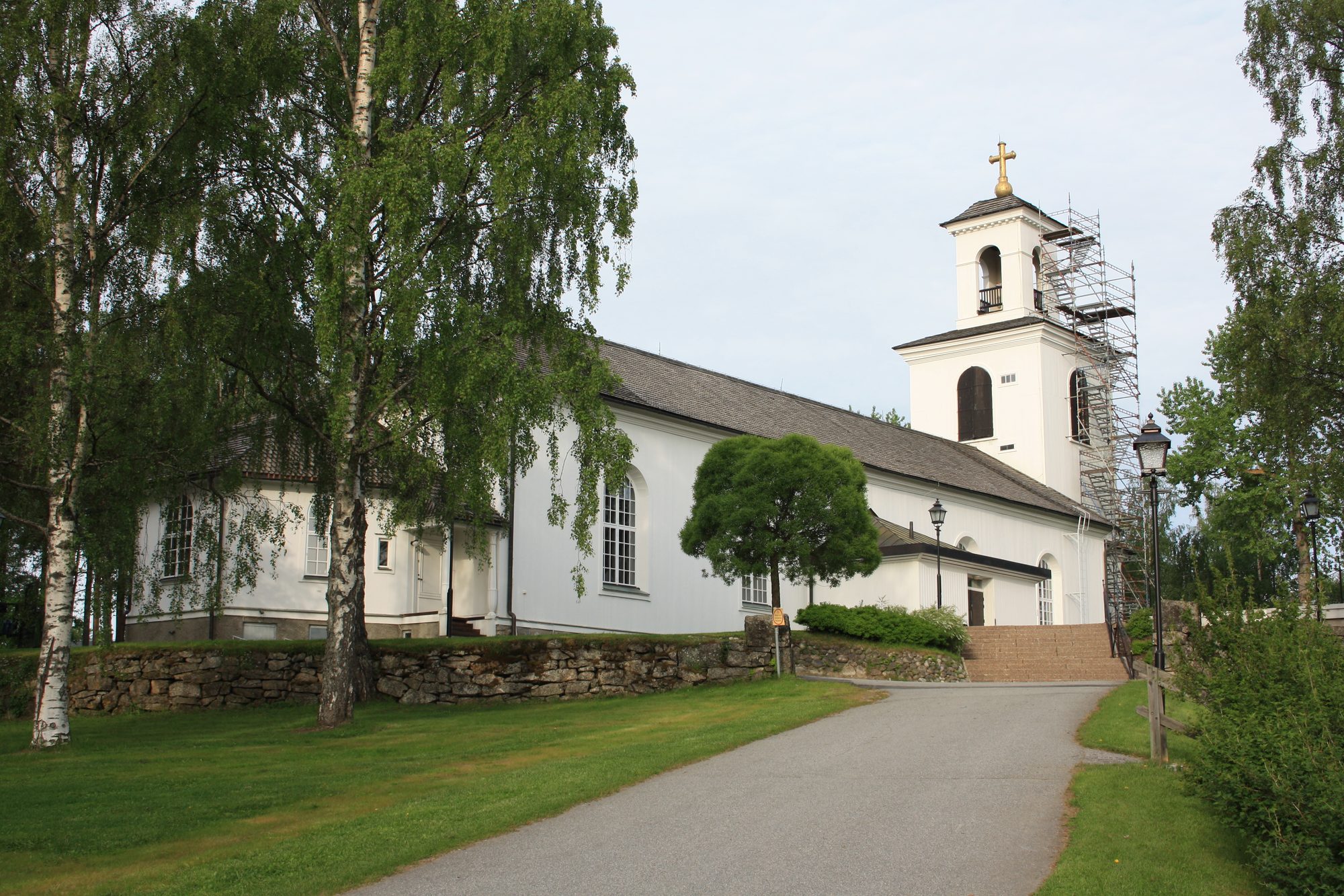 Lycksele kyrka, träkyrka med torn mot sommarhimmel.