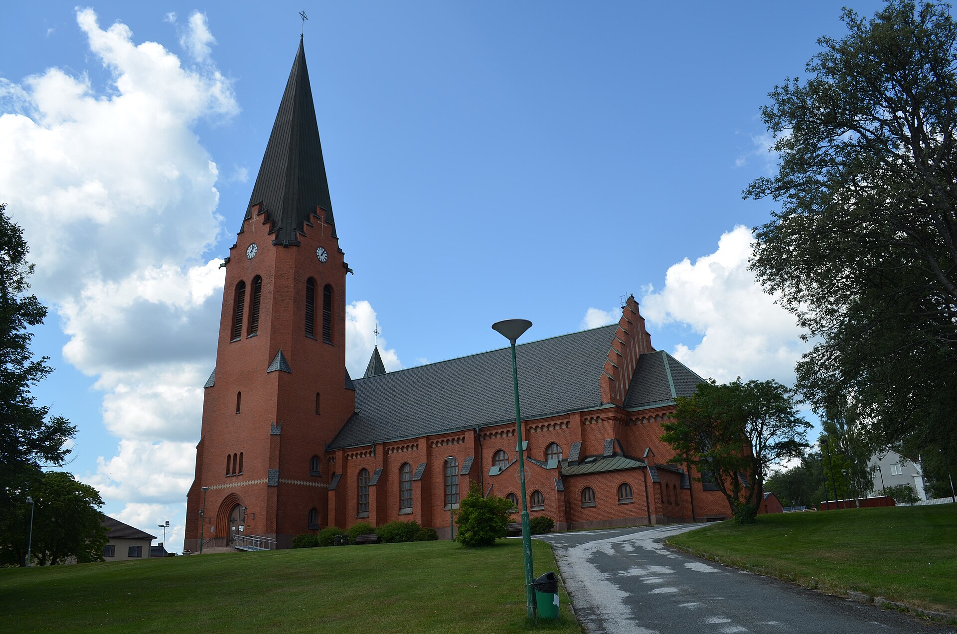 Nässjö stadskyrka, tegelkyrka med torn mot sommarhimmel.