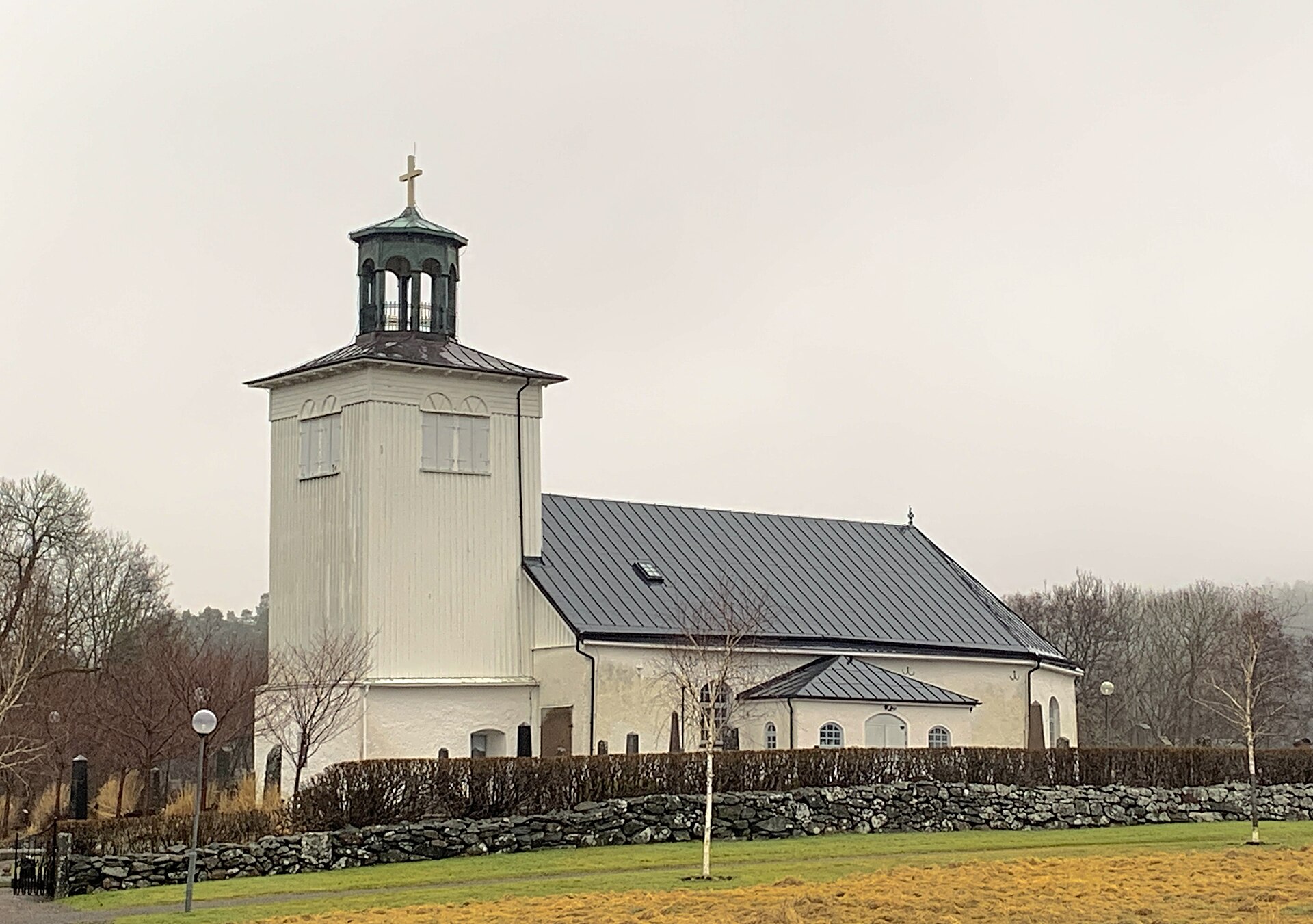 Nödinge kyrka i Ale, vit kyrka med svart tak och kyrkogård.