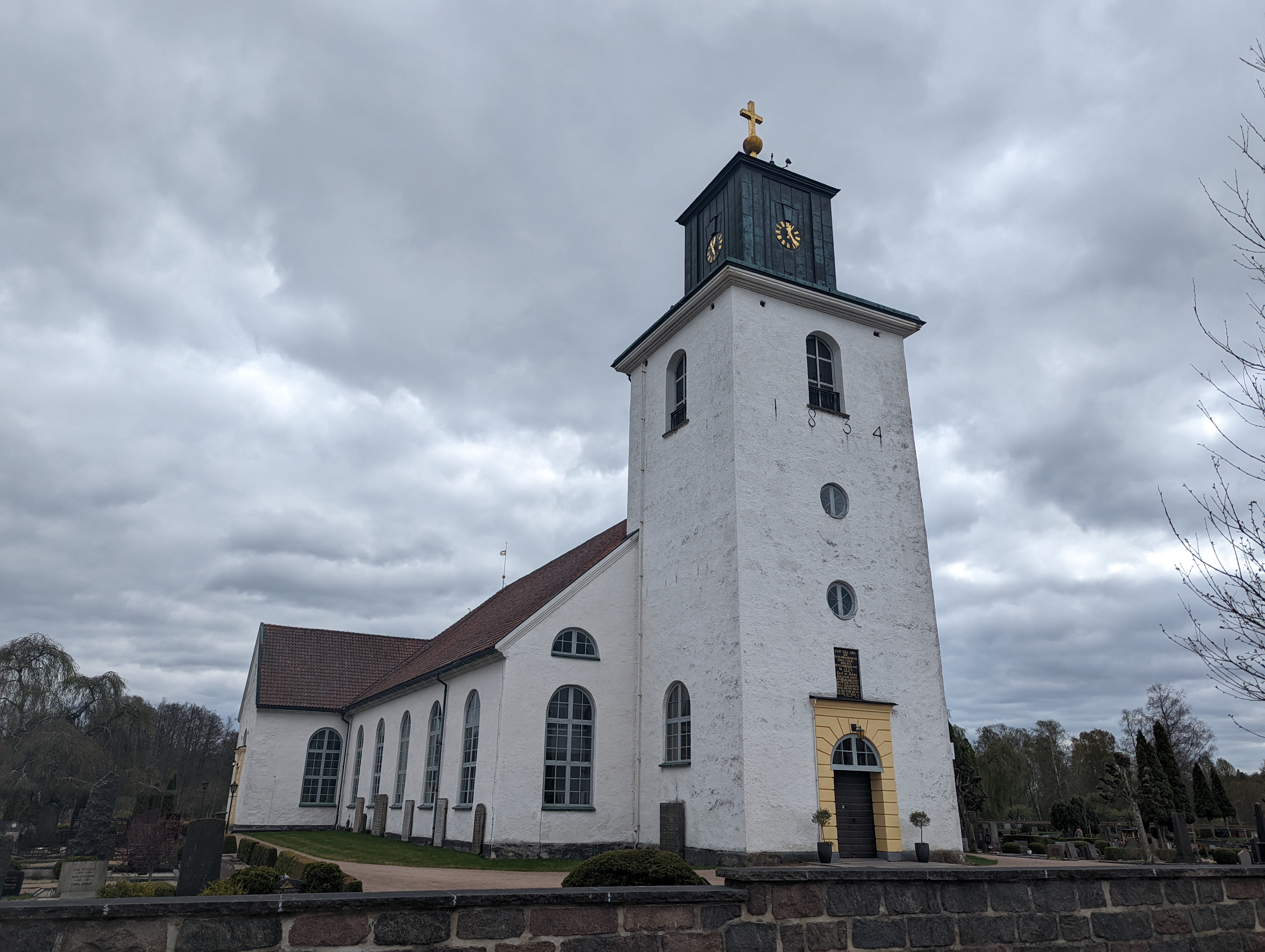 Osby kyrka, stenkyrka med torn mot himlen.