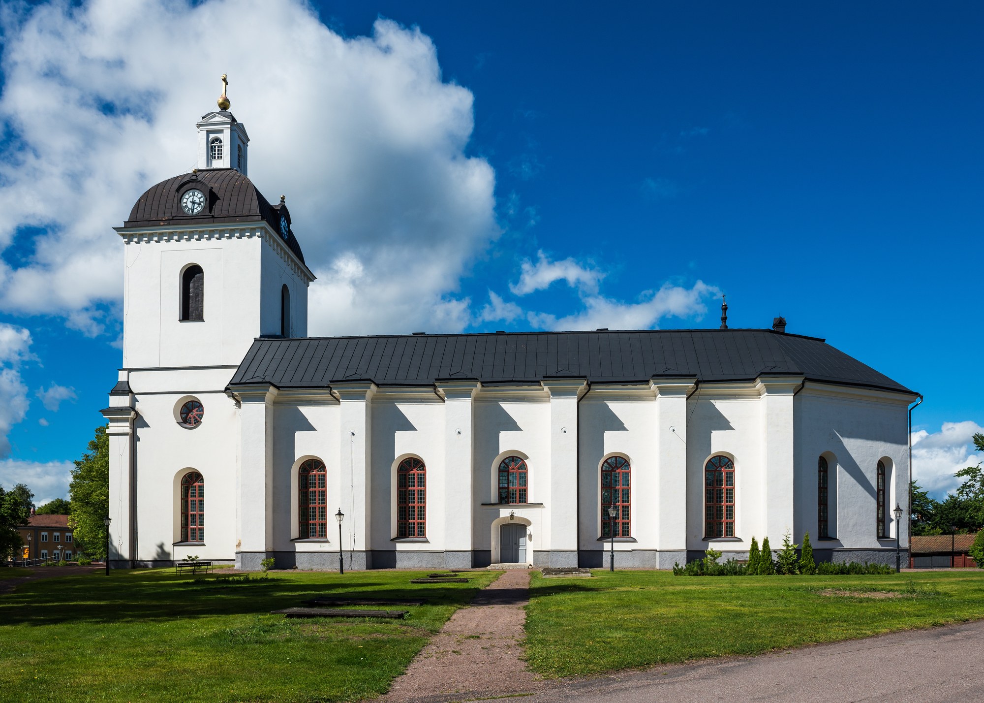 Säters kyrka, stenkyrka med torn mot himlen.