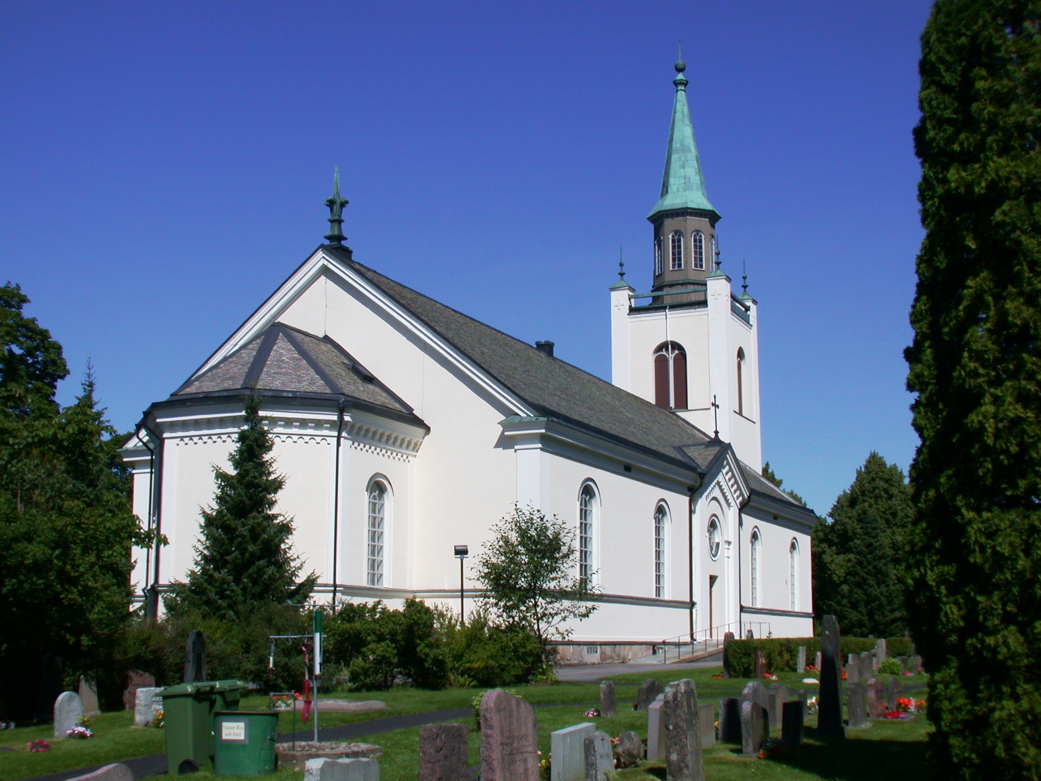 Silbodals kyrka i Årjäng, vit kyrka med svart tak och kyrkogård.