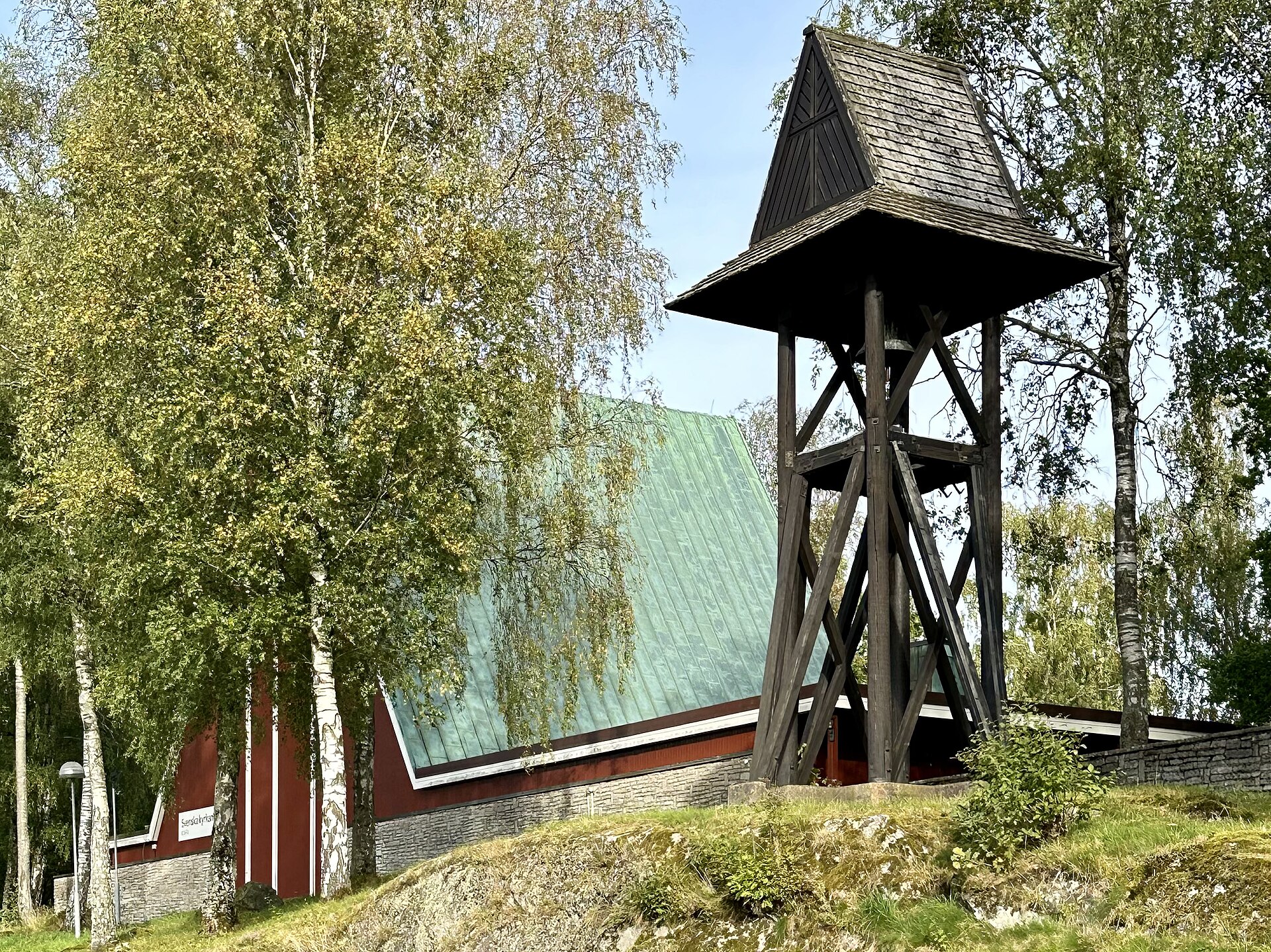 Sjöbo kyrka och klockstapel, vit kyrka med svart tak mot himlen.