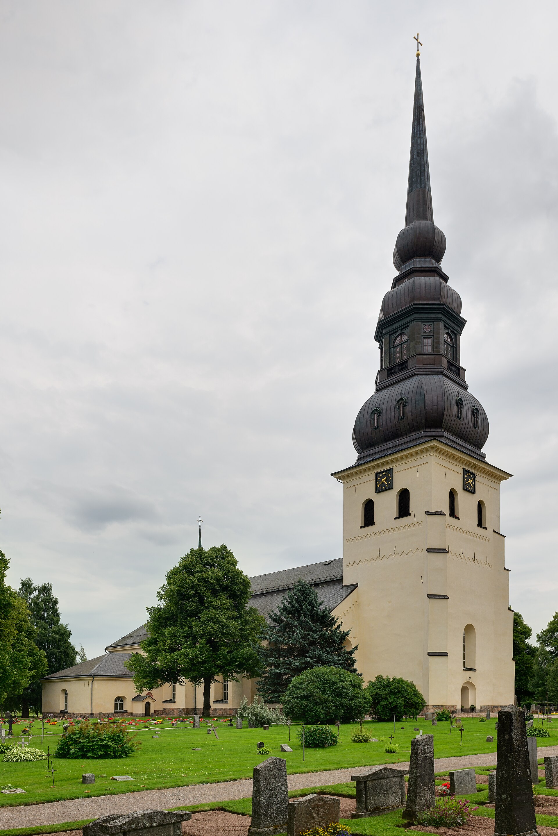 Stora Tuna kyrka i Borlänge, stenkyrka med torn mot sommarhimmel.