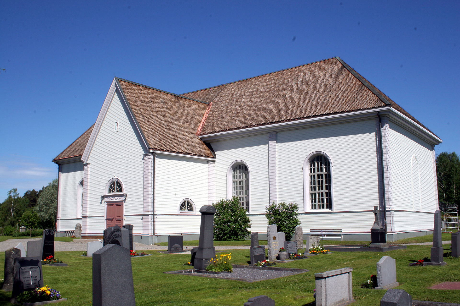 Vännäs kyrka, träkyrka med torn mot himlen.