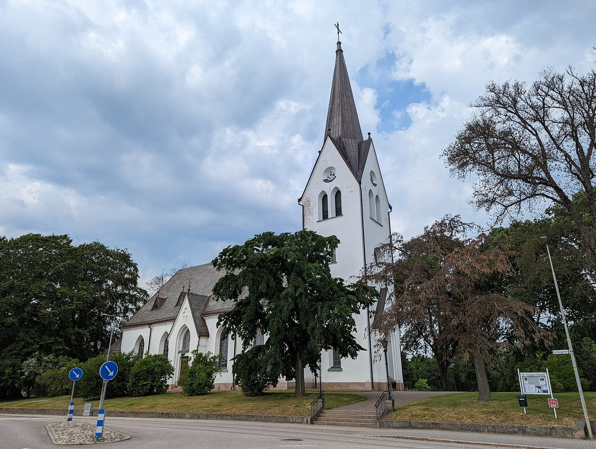 Vara kyrka, stenkyrka med torn mot sommarhimmel.