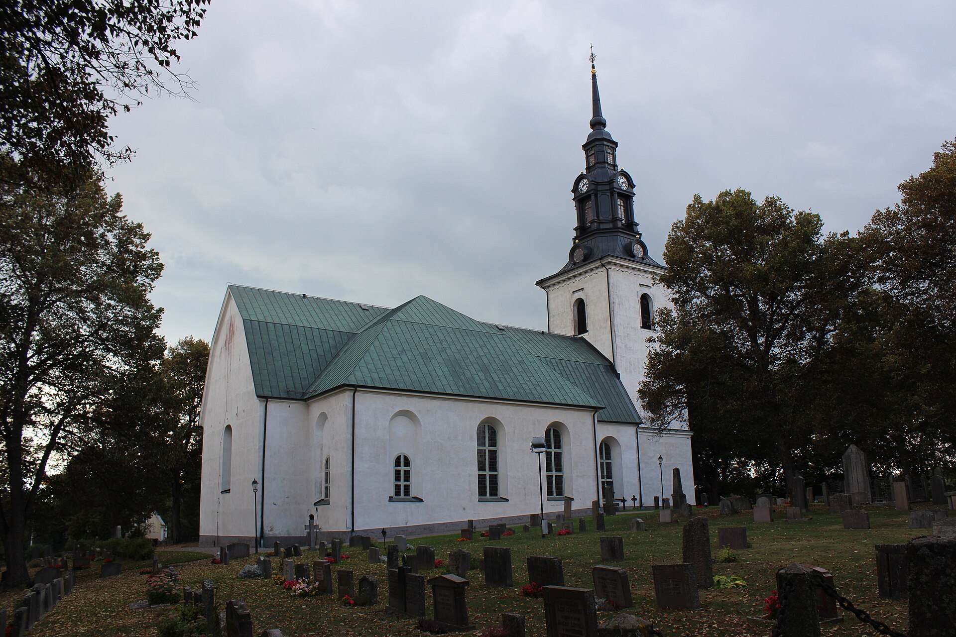 Västerlövsta kyrka i Heby, vit kyrka med svart tak och torn.