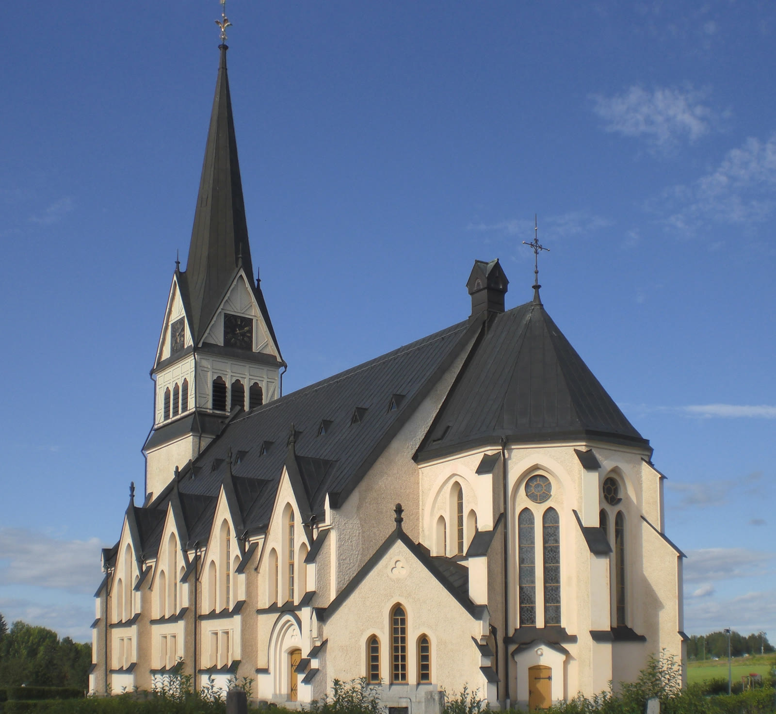 Vindelns kyrka, träkyrka med torn mot sommarhimmel.